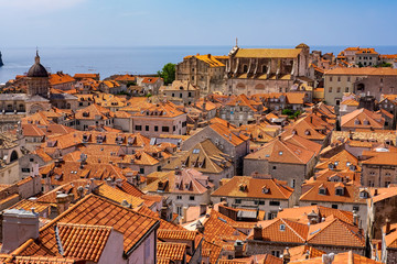 Obraz premium Stone houses with red roofs in old historic Dubrovnik city, Dalmatia, Croatia, blue Adriatic Sea and blue summer sky, the most popular touristic destination
