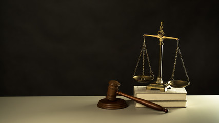 Law and Justice concept. Mallet of the judge, books, scales of justice. Gray stone background, reflections on the floor, place for typography. Courtroom theme.