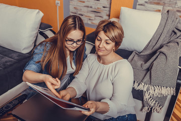 Mother and teenage daughter doing homework together at home