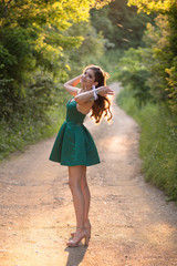 Beautiful brunette girl in glamorous green dress and high heels, shoes in nature. Ready for prom night - obrazy, fototapety, plakaty