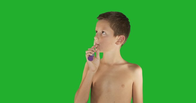Beautiful boy brushing teeth on green screen.