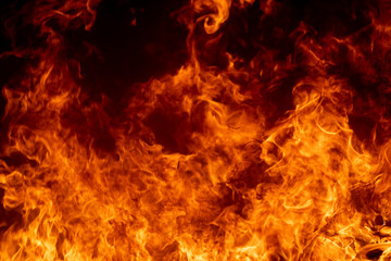 Close up hot fire flame burning glowing on black dark background, fire flame on full flame photo, beautiful abstract fire wallpaper or graphic background, panorama view of blaze glowing flame