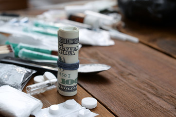 Roll of hundred dollar bills on background of narcotic drug dealer stuff