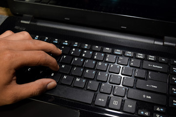 Fototapeta na wymiar Hacker typing code on laptop keyboard with his fingers