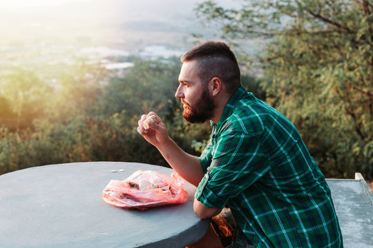 Bearded Guy Eating Some Pie, Resting On The Bench Enjoying The View.