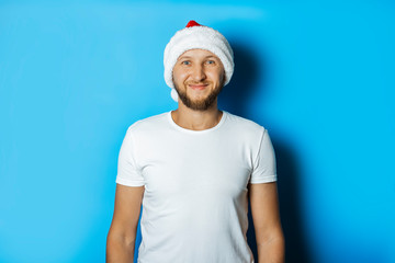 Man in a hat of Santa Claus on a blue background. Concept of winter, autumn, cold, Christmas, winter holidays