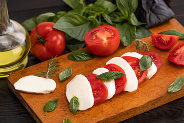 Mozzarella cheese, basil and tomato on slate stone board, copy space. Ingredients for Caprese salad