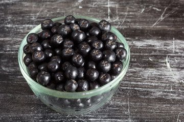 Close up chokeberries in glass bowl on black background