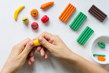 Woman hands making soften and warm piece of polymer clay on white background