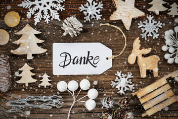 One White Label With German Text Danke Means Thank You. Frame Of Christmas Decoration Like Tree, Sled, Star And Fir Cone. Wooden Background With Snowflakes