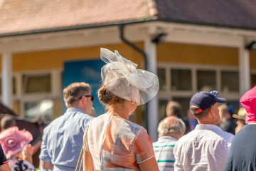 Frau mit weissen Hut wartet auf Siegerehrung nach dem Pferderennen