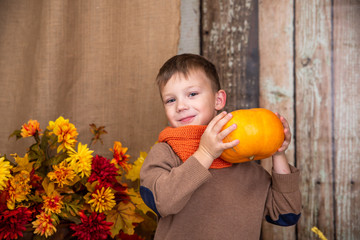 portrait of a boy in orange scarf posing and laughing with pumpkin