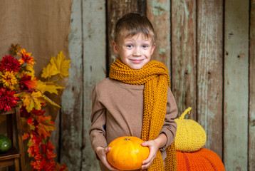 a boy in a yellow scarf with an orange pumpkin