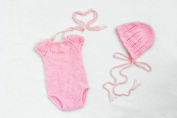 Baby clothes for newborn in pink pastel colors on white wool background. Set of baby clothes. Body, Hat for newborn