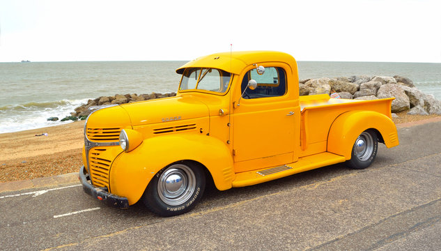  Classic Yellow Dodge  pickup truck on seafront promenade with sea in background