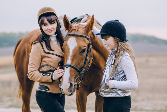 First lessons of horseback riding. Mom and daughter learn to ride a horse.  
