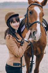 First lessons of horseback riding. Young beautiful girl riding a horse in a field.