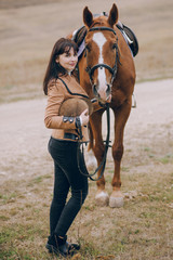 First lessons of horseback riding. Young beautiful girl riding a horse in a field.