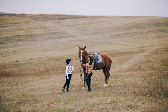First lessons of horseback riding. Mom and daughter learn to ride a horse.  