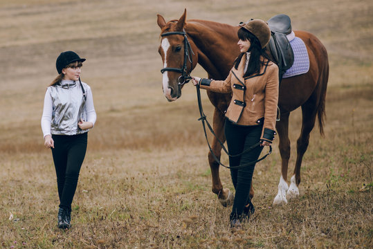 First lessons of horseback riding. Mom and daughter learn to ride a horse.  