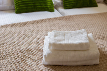 Stack of clean white towels on bed. Cotton soft white towel in hotel