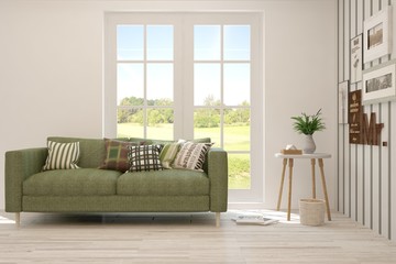 Stylish room in white color with sofa and summer landscape in window. Scandinavian interior design. 3D illustration
