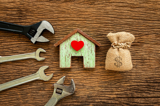 Wooden house with red heart and wrench and money bag put on the old wood, Loan for construction real estate and renovate the new home for family concept.