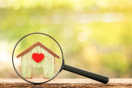 Magnifying Glass With Home Model With Red Heart Put On The Wood On Bokeh Background, Loan For Real Estate And Searching For Buy A New House To Family In The Future Concept.