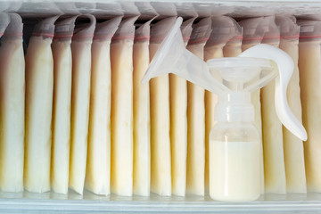 Stock of breast milk frozen in storage bags and a pump bottle for a new baby of family with love in the freezer of refrigerator.