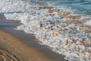 Close-up of a wave hitting a beach in warm sunset light
