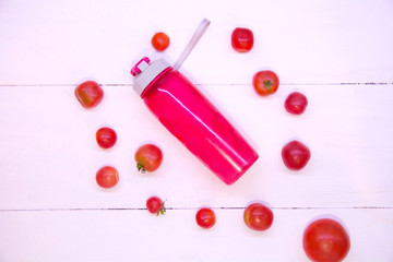 Naklejka na ściany i meble Pink tomato smoothie. Sports pink bottle on a white background top view. Sports nutrition and diet. Detox Raw Food Concept. Tomatoes around a pink plastic bottle