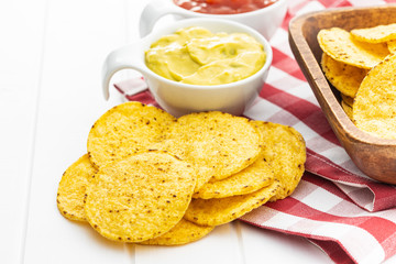 Round nacho chips and avocado dip. Yellow tortilla chips and guacamole in bowl.