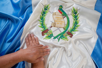 Detail of hands on top of the national flag of Guatemala- proud to be Guatemalan - brunette hands