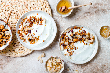 Breakfast bowls with granola, yogurt, coconut chips and honey. Healthy vegan, vegetarian breakfast table