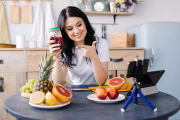 Attractive, athletic, smiling, young woman eating healthy and preparing fruit smoothies