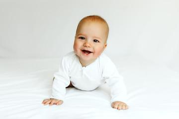 Fototapeta premium Beautiful happy baby smiling in white on the bed.
