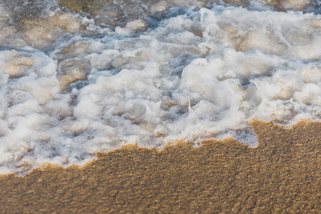 Close-up of a wave hitting a beach in warm sunset light