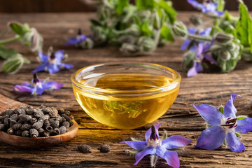 A bowl of borage oil and borage seeds and flowers
