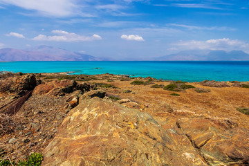 Fototapeta na wymiar abandoned beach , rocks on coast, beautiful turquoise sea , deep blue sky with clouds and mountains on background, Mediterranean landscape