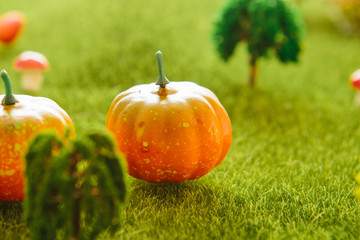 Orange plastic pumpkins on a green meadow with green grass. Macro shooting. Fairy tale.