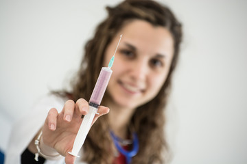 Young smiling caucasian nurse with a syringe with medication in her hand in the infirmary.