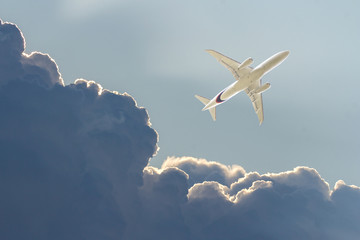Commercial airplane in a dark stormy sky. White plane flying in thunderclouds. Bottom view. Tourist...