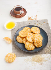Traditional japanese rice chips cookies with honey and soy sauce on a blue ceramic plate and a cup of coffee on a white wooden background. side view.