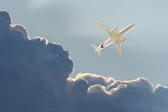 Commercial airplane in a dark stormy sky. White plane flying in thunderclouds. Bottom view. Tourist airliner flies on a thunderstorm and in a turbulence zone