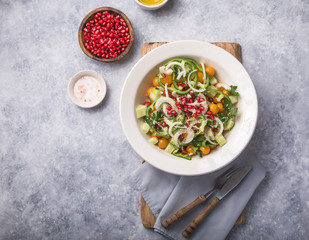 Salad with cucumber, tomato cherry, pomergranate, onion and paprika. Top view on grey concrete background.