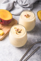 Yellow mango yogurt or smoothie on blue background with copy space left. Turmeric Lassie or lassi in glass. Banner