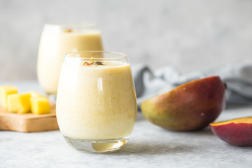 Yellow mango yogurt or smoothie on blue background with copy space left. Turmeric Lassie or lassi...