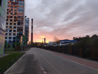 at sunrise in the light of dawn with houses and pipes of a plant in the distance