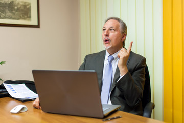 Senior manager finding a solution while working at his laptop in his office