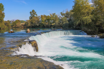 under a bright blue sky you can see the waterfall of Manavgat